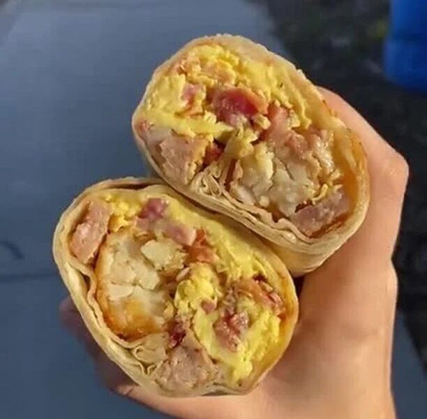 A classic breakfast burrito with ham, eggs and tots cut in half